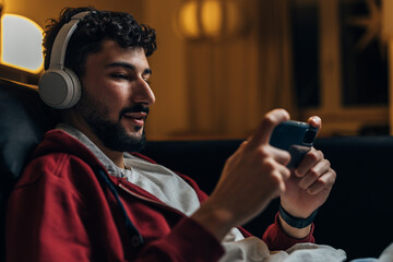 Side view of a young man playing video games on his phone