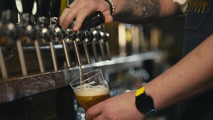 Slow motion close up of bartender pouring beer. After closing the tap for pouring beer, the last drops fall spectacularly into the glass. High quality 4k footage