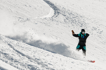 active man snowboarder fast and skilfully descends down a snowy mountain slope