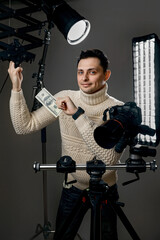 photographer with digital camera on tripod holding hundred dollar bills