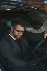 Handsome businessman driving car before buying