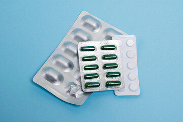 Several blisters with pills on a blue paper background