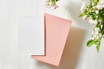Mockup invitation or blank greeting card and envelope with spring flowers on a light background