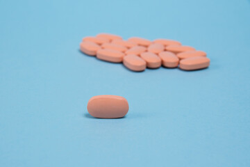 Pink pill macro on a blue paper background and many pills in the background