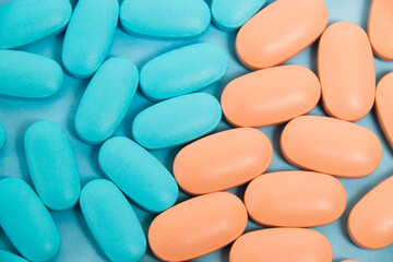 Pattern, blue and pink vitamins in pills for men and women on blue paper flatlay background. The...