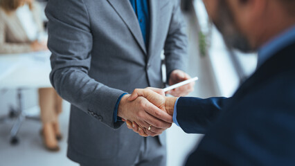 Business people in office suits standing and shaking hands, close-up. Business communication...