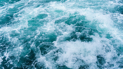 Fototapeta na wymiar White splash foams behind a ship engine on the sea. Foam bubbles on sea water surface .