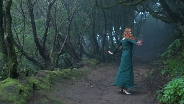 Beautiful woman in an elf costume is walking in a magic green enchanted forest.