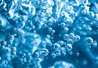 Close up of transparent air bubbles in water in blue tone.