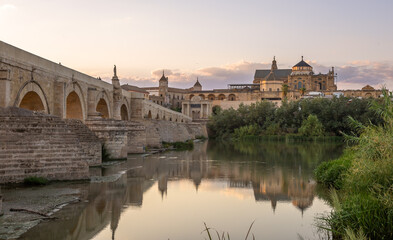 Obraz premium Exposure at sunset of the Roman bridge of and the Mosque–Cathedral of Cordoba in the background with the Guadalquivir river in the foreground