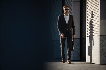 Elegant handsome man in classic suit standing near the office building.