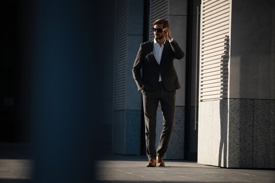 Elegant handsome man in classic suit standing near the office building.