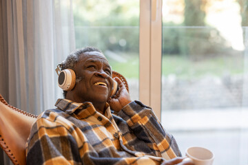 elderly pensioner at home listening to music with headphones