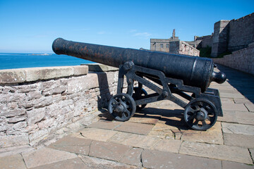 Cannon pointing out towards sea in the grounds of Bamburgh Castle, Northumberland, UK