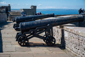 Cannons pointing out towards coast and sea in the grounds of Bamburgh Castle, Northumberland, UK