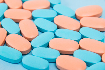 Pattern, blue and pink vitamins in pills for men and women on blue paper flatlay background. The concept of differences in the needs of the female and male gender