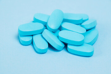 Many pills, vitamins for men on blue background, side view