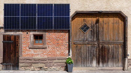 Neue Solarpanels an der Fassade von einem alten landwirtschaftlichen Gebäude mit großem...