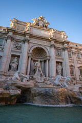 Fontanna di Trevi w Rzymie w słoneczny i bezchmurny dzień. Zasilana wodą z akweduktu rokokowa fontanna z rzeźbami, ukończona w 1762 roku – projekt Nicoli Salviego.