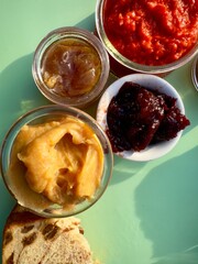 Sweet lime butter, red pepper spread, sour cherry jam, small jar Meyer lemon jelly with pieces of raisin bread - 573674878