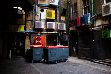 Urban landscape shot of garbage bins surrounded by air conditioning units