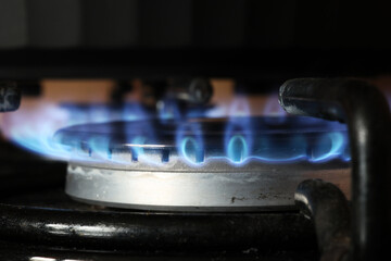 Spalanie gazu ziemnego na kuchennej kuchence gazowej. Panel ze stali z pierścieniowym palnikiem gazowym na czarnym tle. Blisko.  - obrazy, fototapety, plakaty