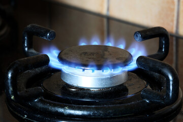 Spalanie gazu ziemnego na kuchennej kuchence gazowej. Panel ze stali z pierścieniowym palnikiem gazowym na czarnym tle. Blisko. 