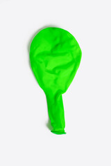 Deflated green balloon on a white isolated background. One uninflated balloon from above. The concept of preparing for the holiday in the form of decoration with balloons or the end of the holiday