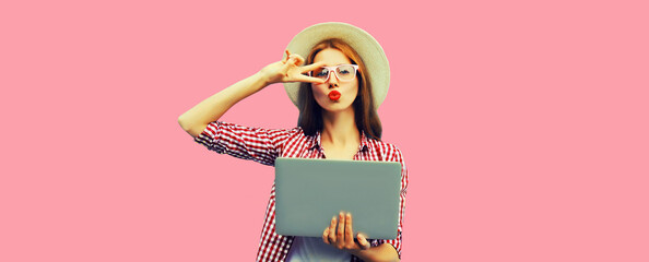 Portrait of modern cool young woman with laptop on pink background