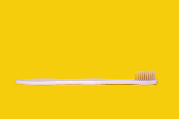 Ecological bamboo toothbrush on a yellow background. Wooden toothbrush without plastic. Waste-free personal care products, dental care concept. Free space for text
