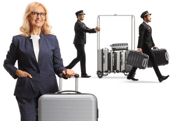 Businesswoman with a suitcase and bellboys pushing a luggage cart