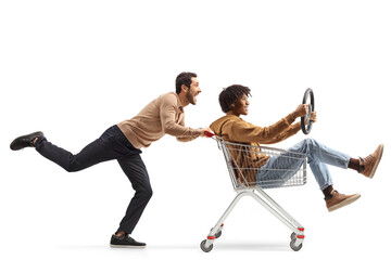 Young caucasian man pushing an african american guy in a shopping cart with a steering wheel