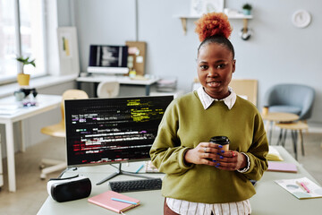 Waist up portrait of black young woman as software programmer smiling at camera in office, copy...