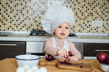 Little girl cooking in the kitchen wearing an apron and a chef's hat