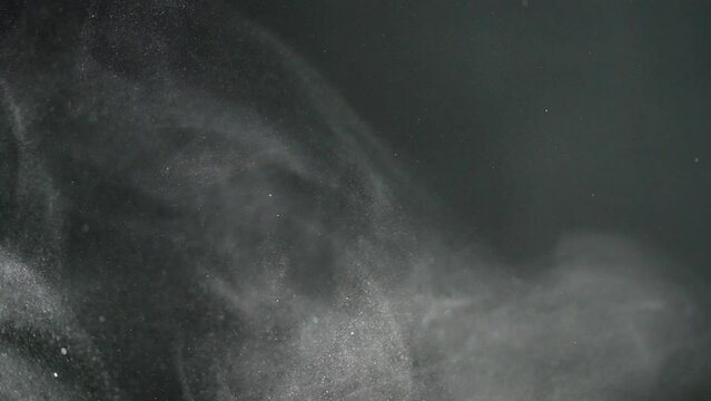Levitation of rotating and twisting particles of sand dust in the air on a black background