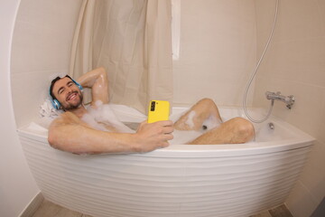 Man listening to music with headphones  in the bathtub