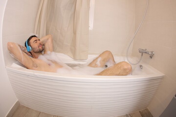 Man listening to music with headphones  in the bathtub 