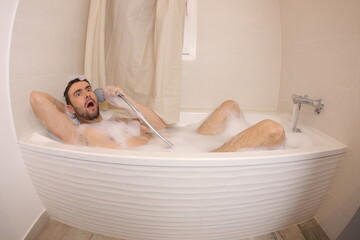 Man pretending to talk on the phone with shower head 