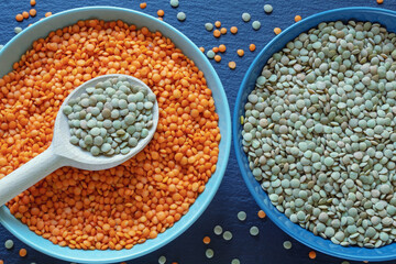 Red and green lentils in plates on dark table