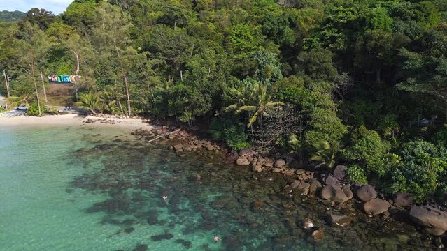 snorkelers explore in turquoise water. Smooth aerial view flight drone