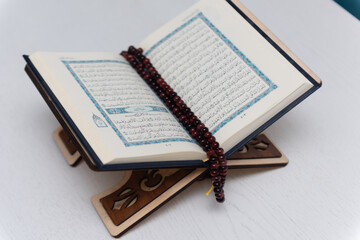 The words on Qoran is arabic words which means the Holy Qoran. Muslim beads and Koran on wooden table. Islamic concept.