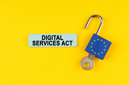 On the yellow surface is an open lock with a key and a sticker with the inscription - Digital services act
