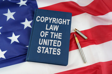 On the US flag lies a pen and a book with the inscription - COPYRIGHT LAW OF THE UNITED STATES