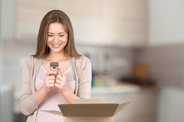 Happy young woman posing with phone and box