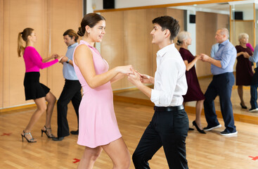 Happy young girl and guy enjoying active lindy hop dance in modern studio. Social dancing concept