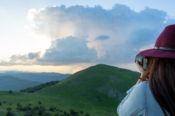 Female Photographer Standing on a Hilltop Viewpoint, Holding Camera, Capturing Awe-Inspiring Mountain Landscape During Springtime Exploration in a National Park