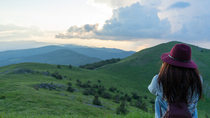 Female Photographer Standing on a Hilltop Viewpoint, Holding Camera, Capturing Awe-Inspiring Mountain Landscape During Springtime Exploration in a National Park