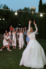 a bride in a white dress throws a wedding bouquet