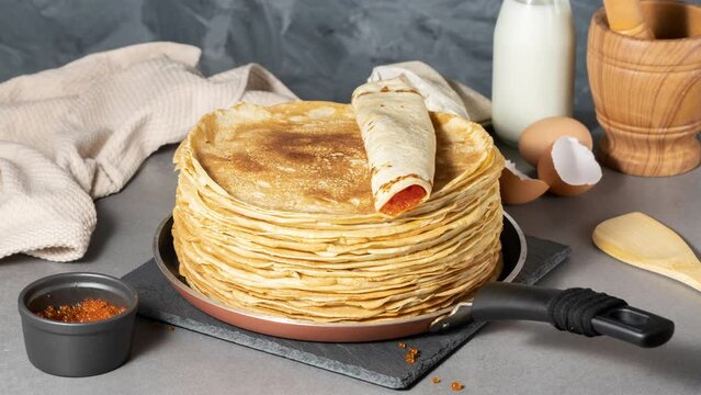 Stack of russian thin pancakes blini with red caviar on grey table. Stop motion animation of stack of Russian blinis, thin pancakes or crepe
