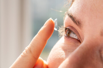Close-up portrait caucasian woman putting on a contact lens. 